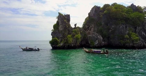 Two longtail boats beside a jagged karst outcrop Видео 71298495