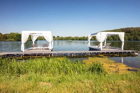 Two lounge chairs on dock overlooking peaceful lake. Kashubia region in Poland Stock Photos