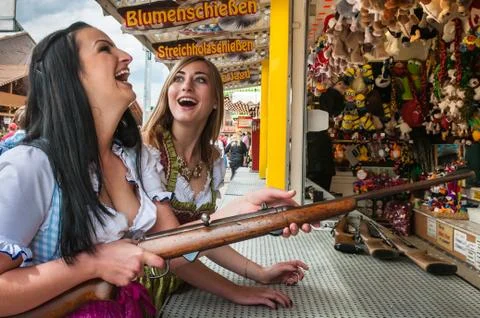 Two lovely girls playing shooting games and having fun at German funfair Stock Photos