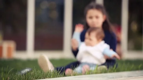 Two lovely sisters in a green grass on a sunny summer day in the park. Stock Footage 75426217