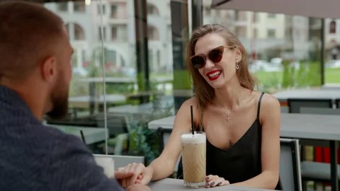 Two lovers are resting in coffee shop, sitting on open terrace and holding hands 스톡 동영상 163332489