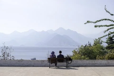 Two lovers are sitting on a bench on the embankment by the ocean Foto stock