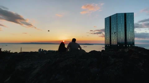 Two lovers are sitting in front of the evening city Stock Footage 282710068