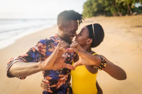 Two lovers on the beach make hearts with their hands and have a passionate .. Stock Photos