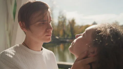 Two lovers exchange loving looks beside shimmering lake surface. Intimate lovers Stock Footage 330431116