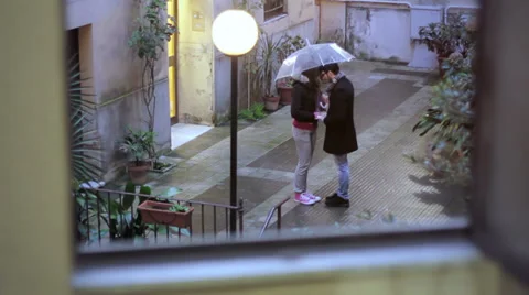 Two lovers holding hands and kissing under umbrella in the rain Stock Footage 35165459