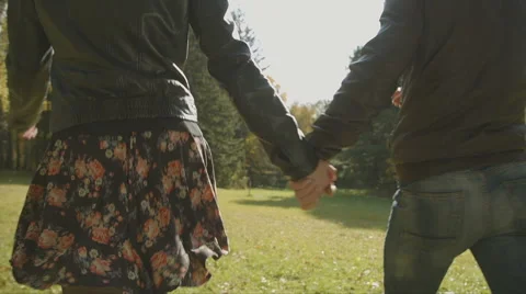 Two lovers holding hands and walking in autumn, close up Stock Footage 55798401