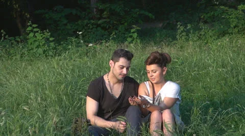 Two lovers sitting on the grass, talking. laughing 스톡 동영상 25505656