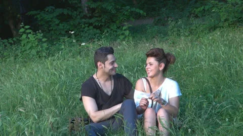 Two lovers sitting on the grass, talking. laughing 스톡 동영상 25505981