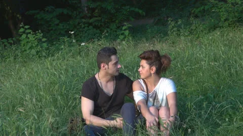 Two lovers sitting on the grass, talking. laughing 스톡 동영상 25506390