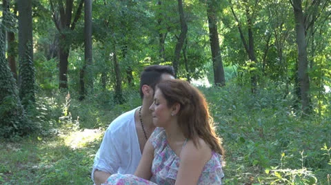 Two lovers sitting on the grass, talking. laughing Vídeos de archivo 25541851