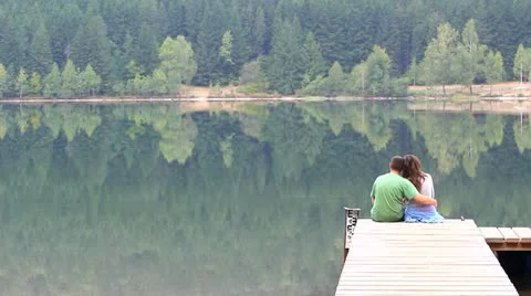 Two lovers sitting on the pontoon and admiring the nature Stock Footage 12301641