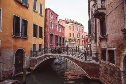Two lovers sitting side by side on a bridge over a canal among old buildings  Stock Photos