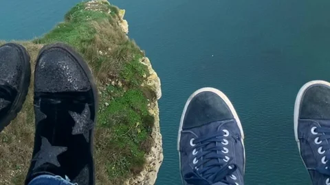 Two lovers. Two pairs of legs over the cliff Stock Footage 127529063