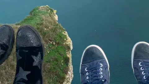Two lovers. Two pairs of legs over the cliff Stock Footage 127529295