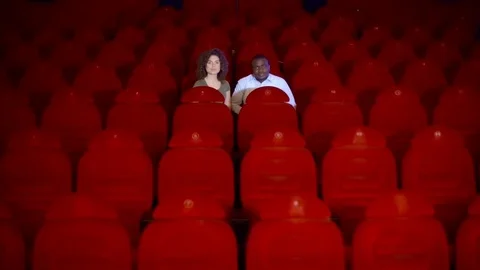 Two loving in the great, empty hall of the cinema with red chairs Stock Footage 75040149