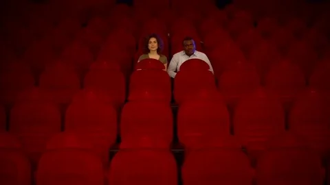 Two loving in the great, empty hall of the cinema with red chairs Stock Footage 75040166