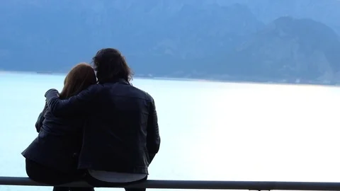 Two loving people sitting on the bench, looking at sunset Vidéo 84598037