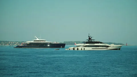 Two luxurious superyachts navigate the clear blue waters of the french riviera, Stockbeeldmateriaal 339818348