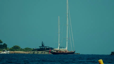 Two luxury yachts and sailing boats navigating on the blue sea near a green Stock Footage 339804507