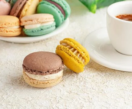 Two macaroons are on the table. In the background, cups with coffee. And plat Stock Photos