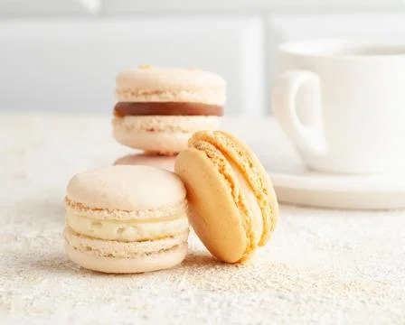 Two macaroons are on the table. In the background, cups with coffee. And tare Stock Photos