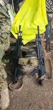 Two machine guns against the background of a yellow flag and an old building Stock Photos