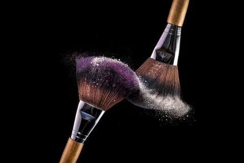 Two make-up cosmetic brushes with white powder explosion on black background. Stock Photos