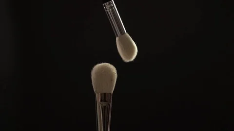 Two makeup brushes with powder on a dark background, slow motion Stock Footage 104502240