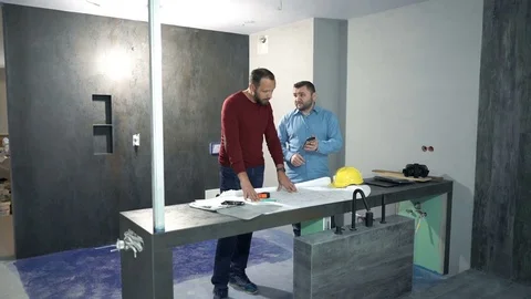Two male architects calculating data, working with smartphone and blueprints Stock Footage 85298866