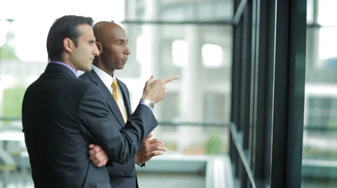 Two male Business Professionals Work Together, while looking out a window Stock Footage