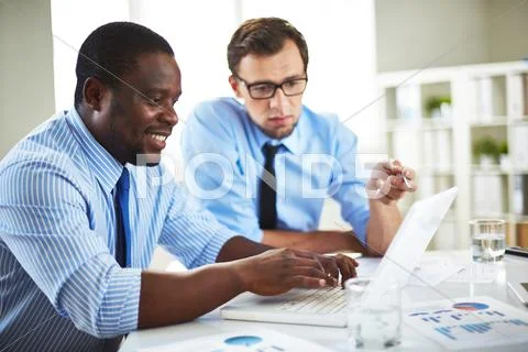 Two male colleagues discussing data on laptop Stock Photos