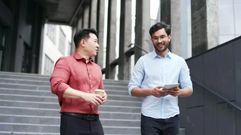 Two male colleagues walking down stairs outside office building discussing  Stock Footage 302893740