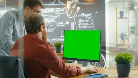 Two Male Developers Talk about Project, while Personal Computer Has Green Screen Stock Footage 82899516