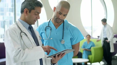 Two male doctors using digital tablet in a hospital meeting area. Stock Footage 36082465