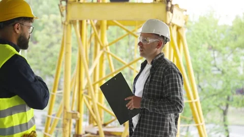 Two male engineers discussing a construction project with a crane Video stock 343450692