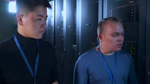 Two male engineers discussing it project and walking along dark room of data Stock Footage 163693416