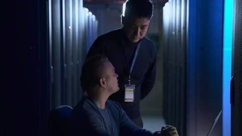 Two male engineers talking and working at table with laptop in big data office Stock Footage 163693368