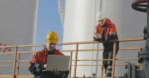 Two male engineers work at modern petrochemical factory using laptop and walkie Stock Footage 108980891