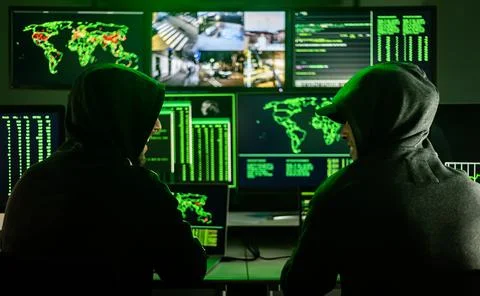 Two male hackers coding virus software in dark room Stock Photos