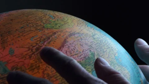 Two male hands moving on a globe looking for countries and places Stock-Footage 102365486