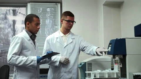 Two Male Scientists Working on Laboratory Test Machine Together Stock Footage 71779436