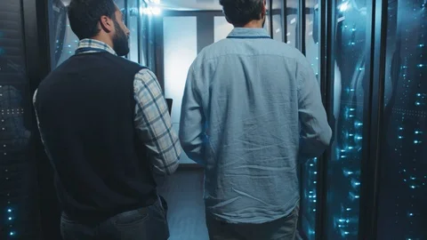 Two male server specialists walking in server room collaborating examining rack Video stock 119278563
