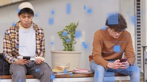Two male students sitting on bench, phones emitting blue digital overlay, one Stock Footage 332577827
