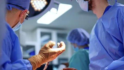 Two male surgeons stand over the operating table facing each other. Stock Footage 321537578