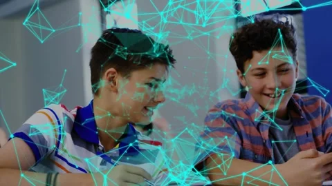 Two male teens in class, right peer pulling smartphone, sharing joke as 動画素材 330355694