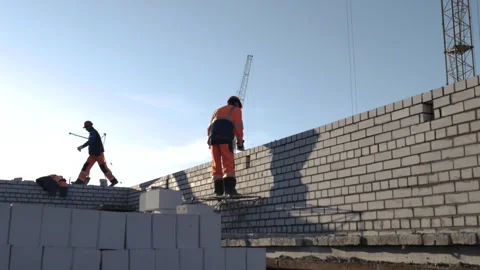 Two male workers doing brick wall on a construction site at daytime Stock Footage 248289858