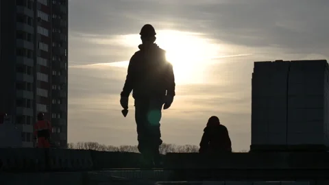Two male workers leaving the frame in a sunset on a construction site Stock Footage 248289994