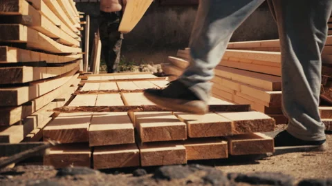 Two male workers stacking long wooden timber boards for drying outdoors Stock Footage 205361419
