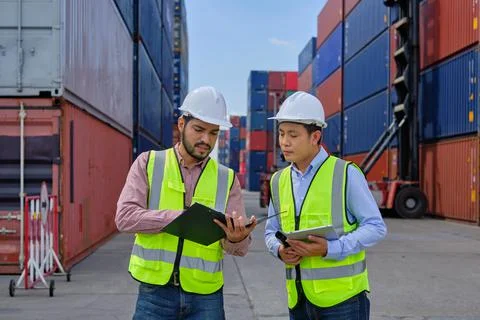 Two male workers work at a logistics terminal with many stacks of containers. Fotos de archivo